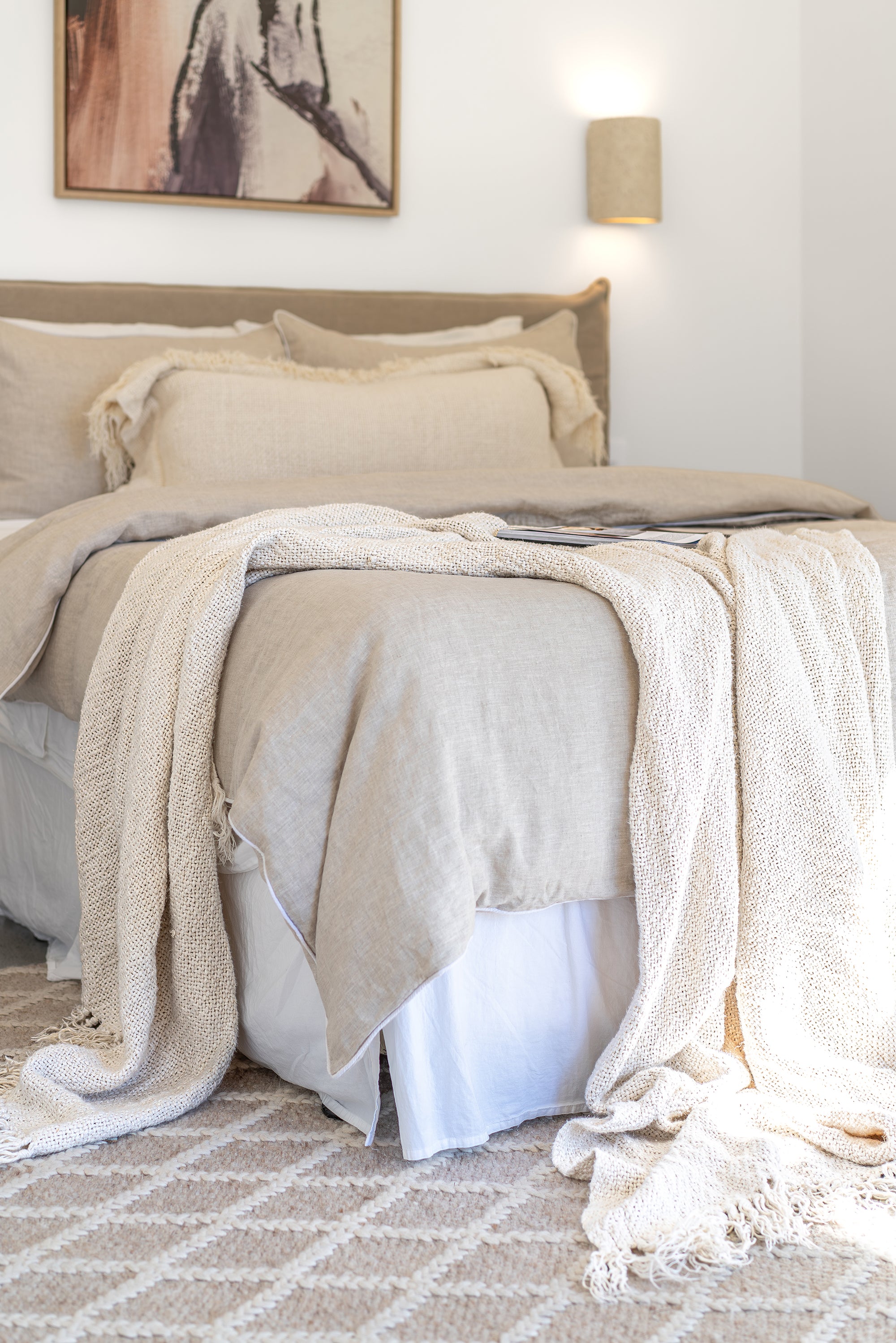 Styled with soft neutral bedding and a chunky knit throw, creating a warm and inviting bedroom atmosphere