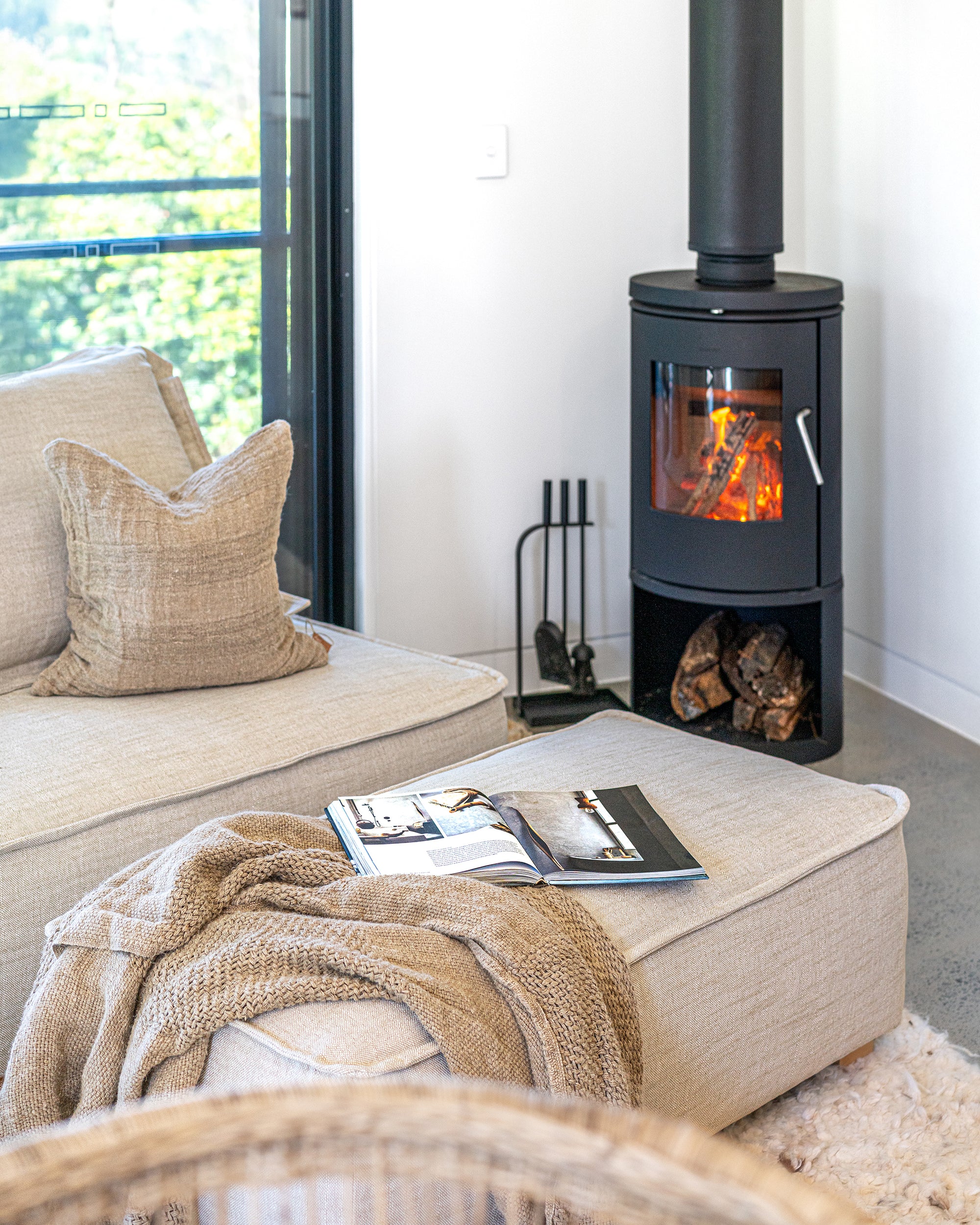 Cosy corner featuring the Johnson Sofa and ottoman styled with a chunky knit throw beside a crackling wood fire, creating a warm and inviting winter retreat