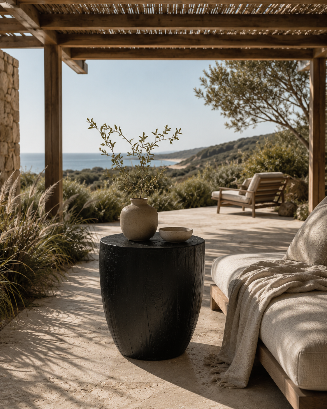 Kisiki Stool in black timber adds sculptural character to a relaxed coastal outdoor retreat overlooking the ocean