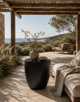 Kisiki Stool in black timber adds sculptural character to a relaxed coastal outdoor retreat overlooking the ocean