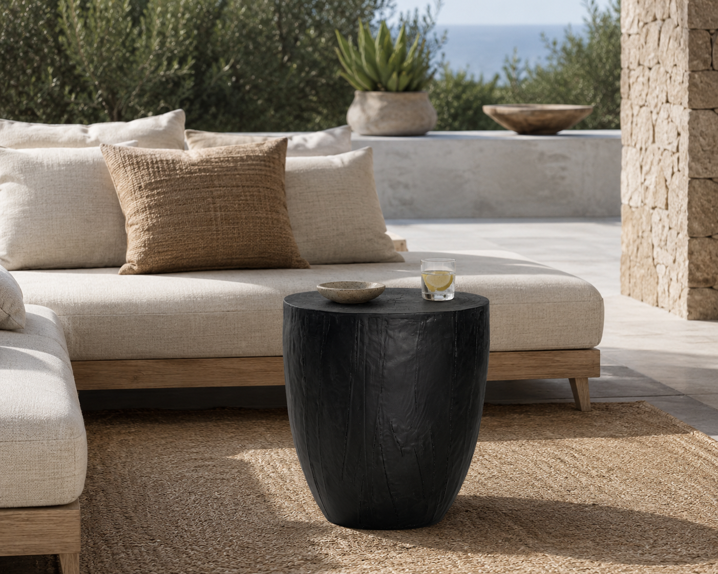 Kisiki Stool in black timber adds sculptural contrast to a relaxed coastal outdoor lounge setting