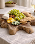 Koro serving board in teak styled with cheese, grapes and crackers on a soft neutral entertaining table setting.