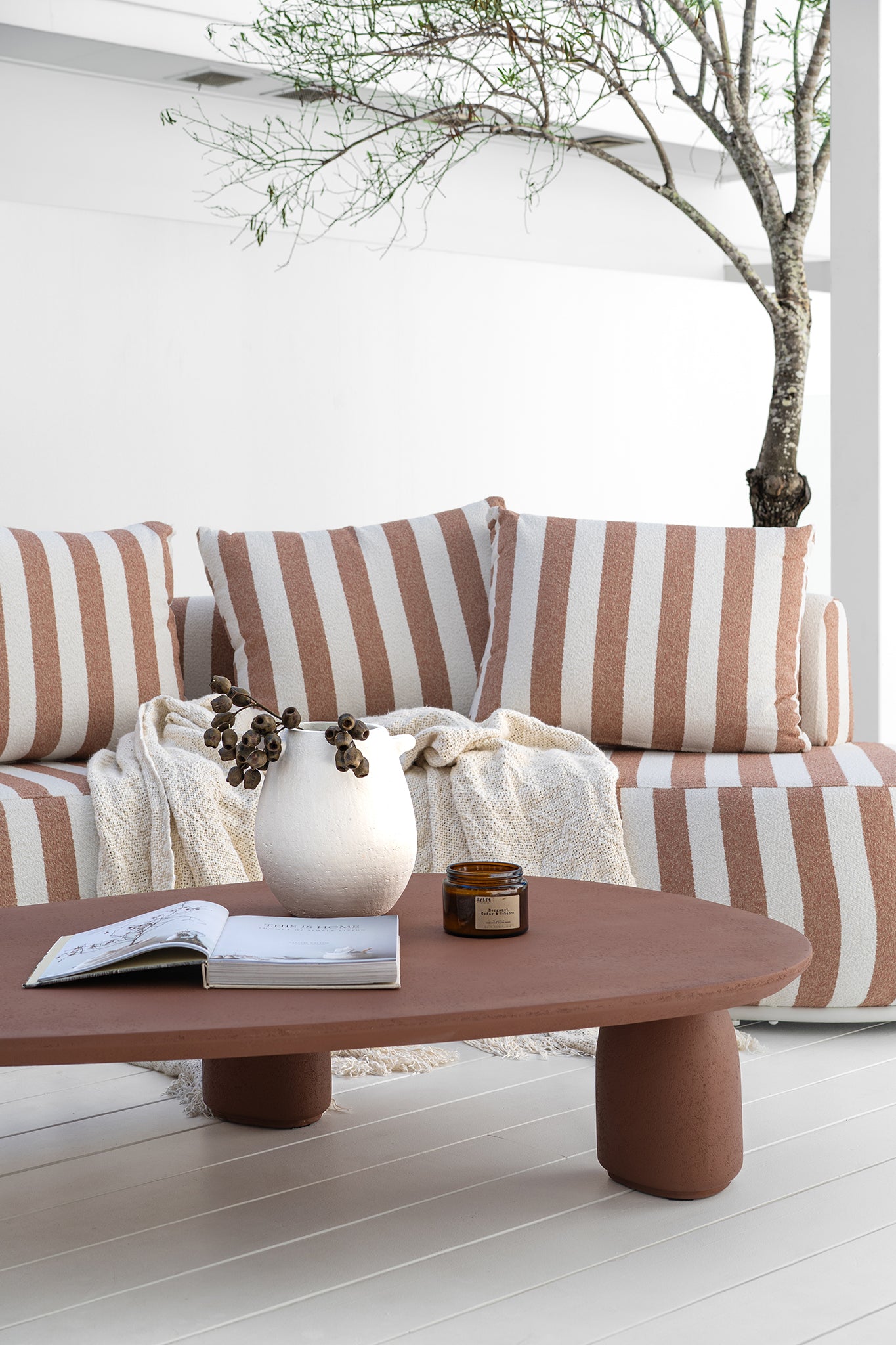 Laguna sofa in cinnabar clay stripe paired with Lantara coffee table creating a warm relaxed outdoor setting with soft earthy tones.