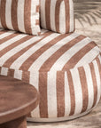 Laguna modular sofa in cinnabar stripe fabric styled outdoors with a lantara coffee table overlooking a coastal view.