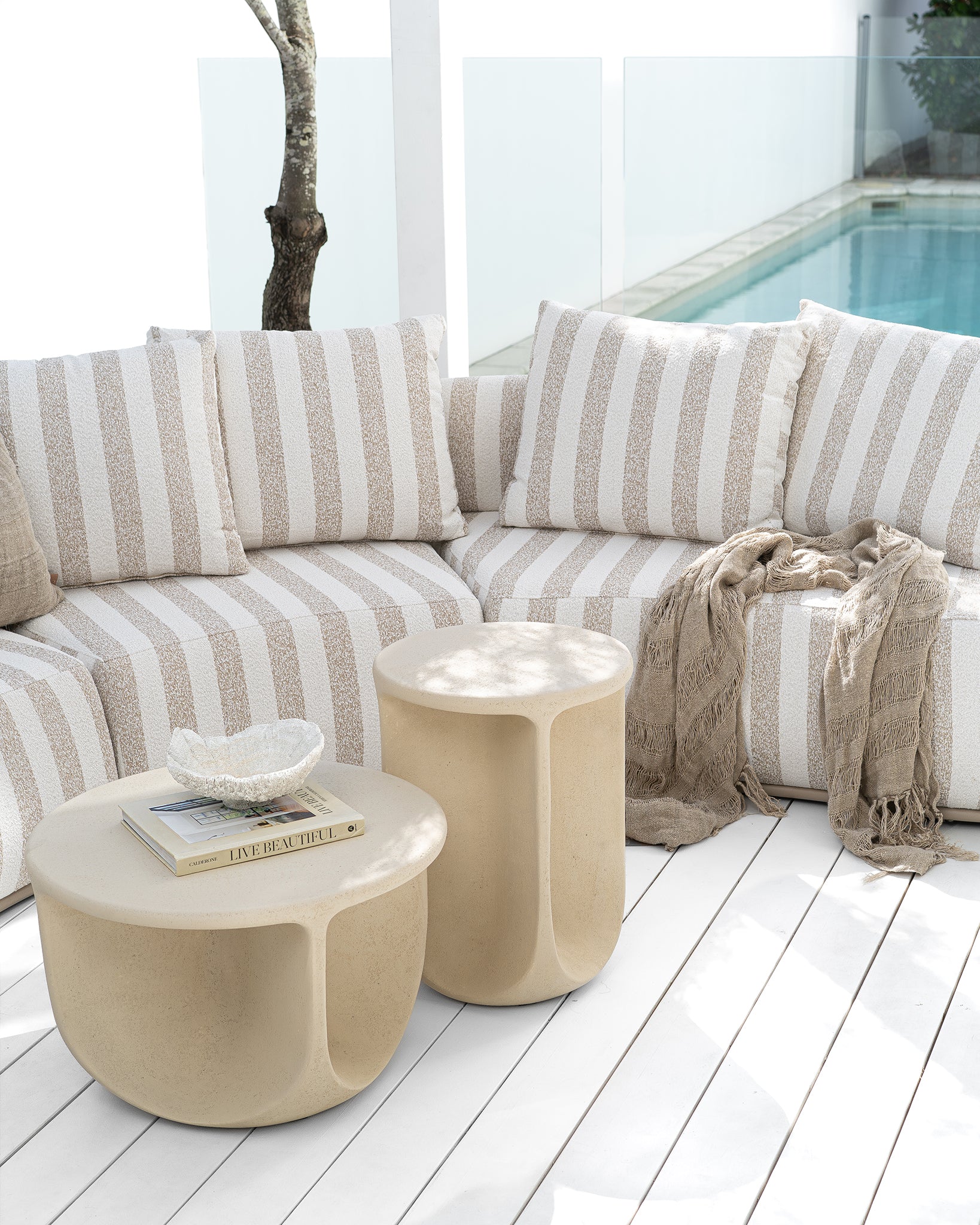 Laguna sofa in sand stripe fabric paired with Berber coffee table and side table in driftstone creating a relaxed coastal outdoor setting.