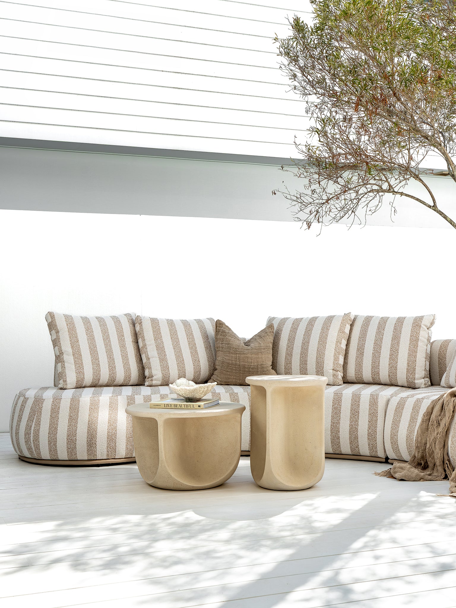 Laguna sofa in sand stripe fabric paired with Berber coffee table and side table in driftstone creating a relaxed coastal outdoor setting.