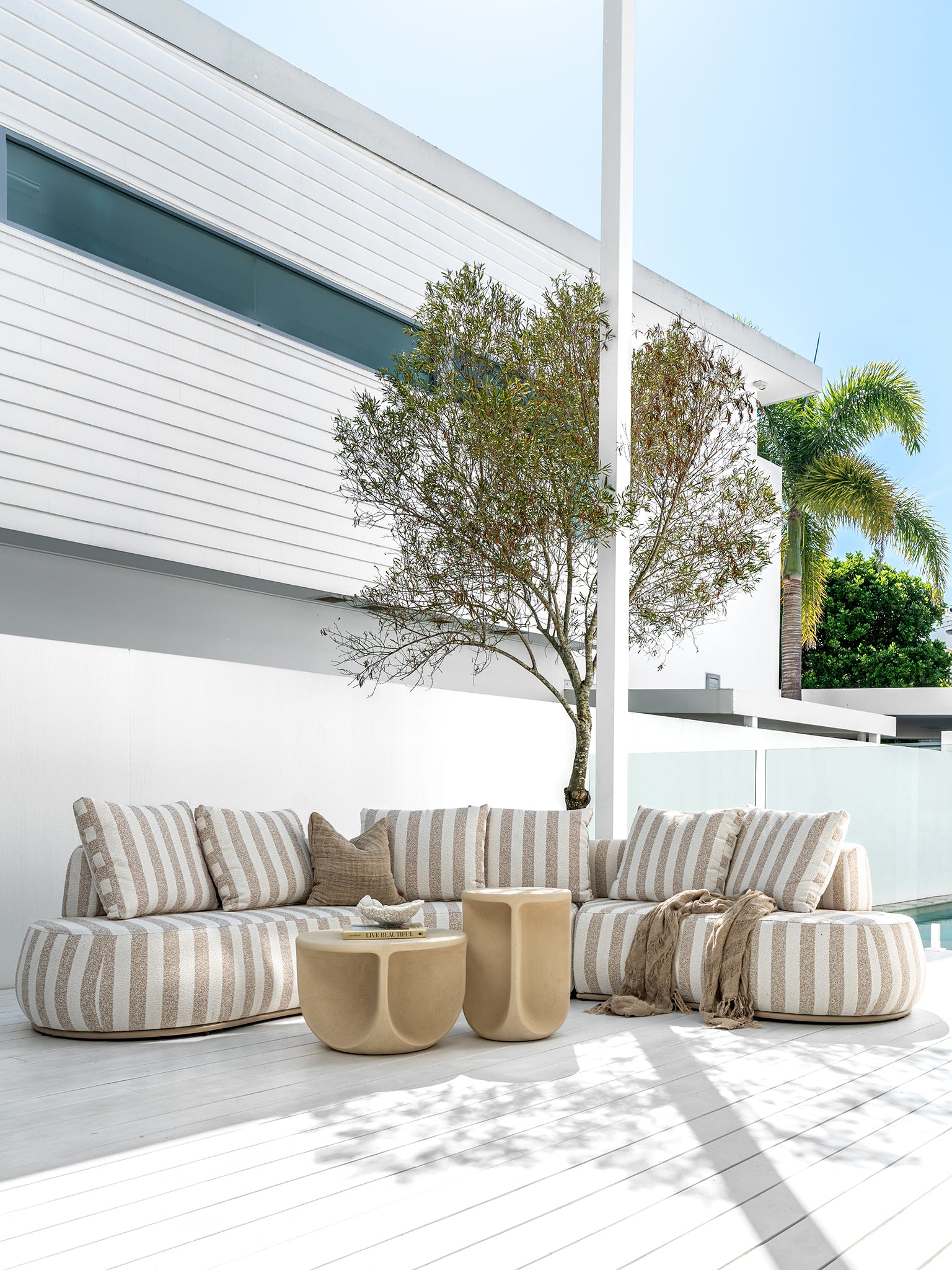 Laguna sofa in sand stripe fabric paired with Berber coffee table and side table in driftstone creating a relaxed coastal outdoor setting.