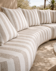 Laguna modular sofa in sand stripe fabric styled outdoors with a round coffee table in a relaxed natural setting.