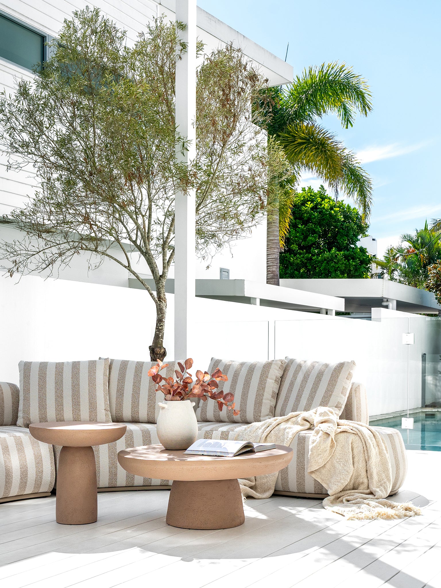 Laguna sofa in sand stripe fabric styled with Tarran coffee table and side table in nomad dune creating a soft neutral outdoor living setting.