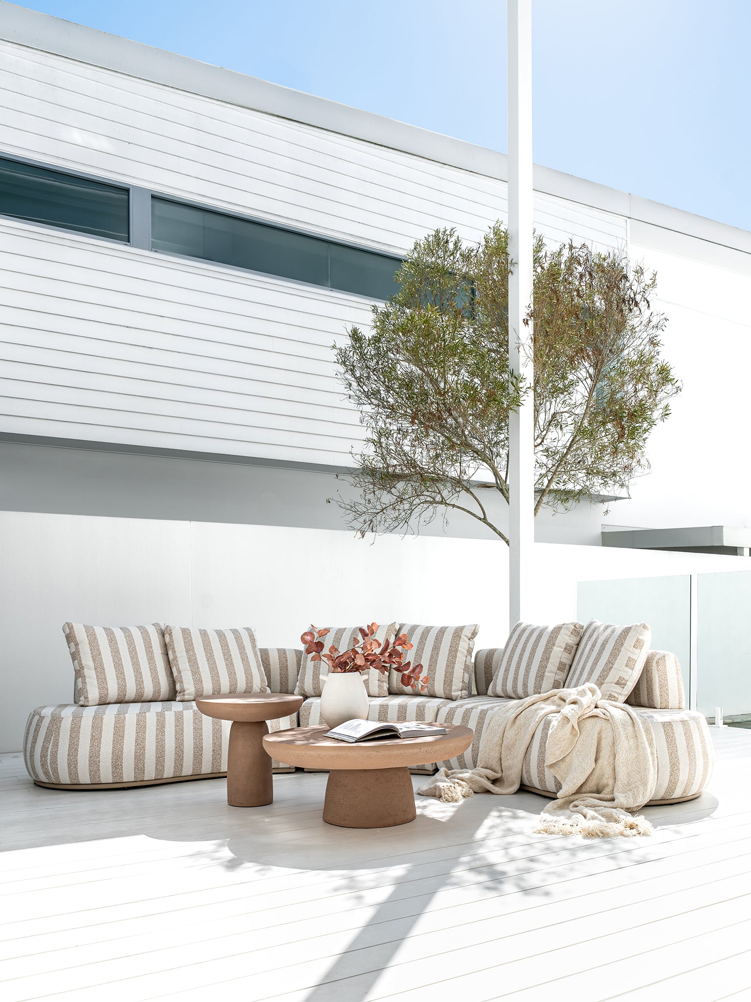 Laguna sofa in sand stripe fabric styled with Tarran coffee table and side table in nomad dune creating a soft neutral outdoor living setting.