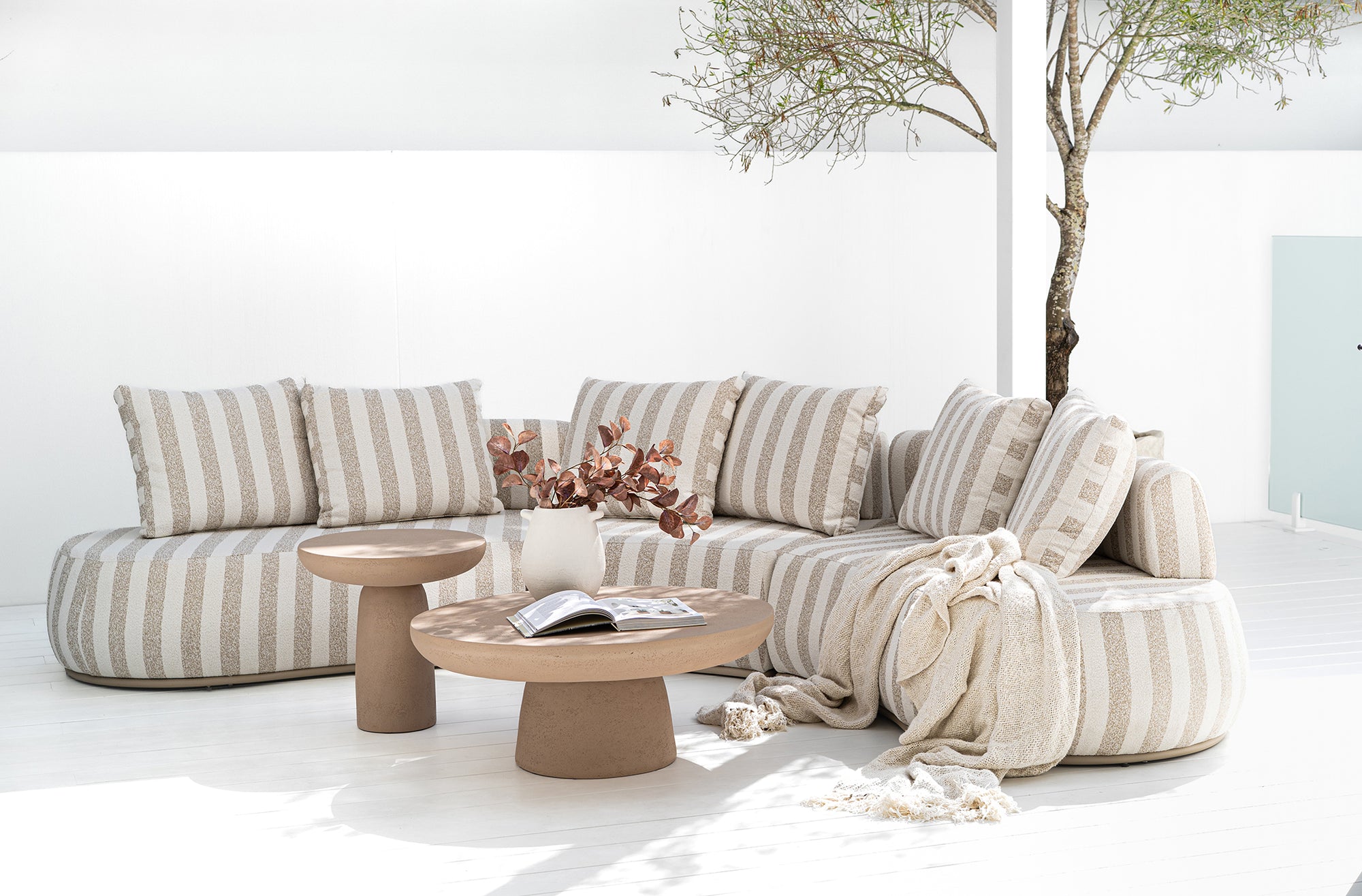 Laguna sofa in sand stripe fabric styled with Tarran coffee table and side table in nomad dune creating a soft neutral outdoor living setting.