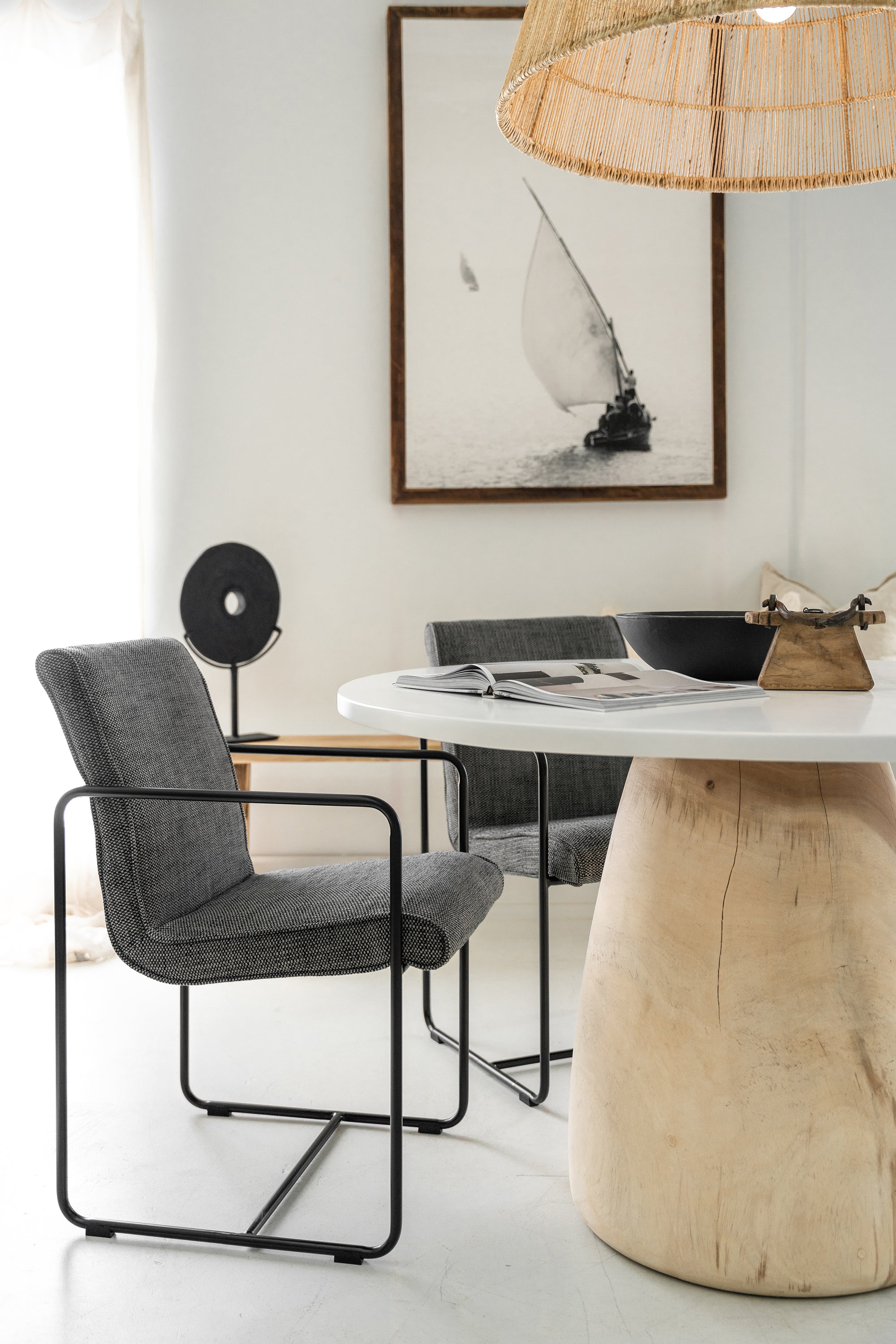 Lalala Armchair with grey upholstered seat and black steel frame styled around a round timber dining table in a modern neutral interior with soft natural light