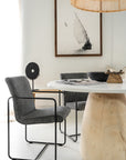 Lalala Armchair with grey upholstered seat and black steel frame styled around a round timber dining table in a modern neutral interior with soft natural light