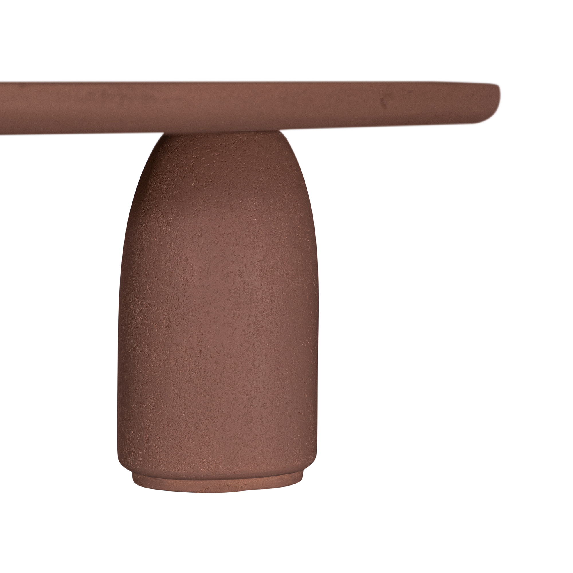 Lantara coffee table in cinnabar clay finish with elongated oval top and three rounded sculptural legs.