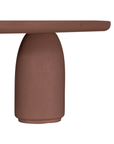 Lantara coffee table in cinnabar clay finish with elongated oval top and three rounded sculptural legs.