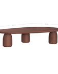 Lantara coffee table in cinnabar clay finish with elongated oval top and three rounded sculptural legs.