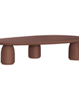 Lantara coffee table in cinnabar clay finish with elongated oval top and three rounded sculptural legs.
