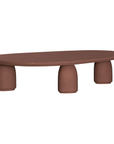 Lantara coffee table in cinnabar clay finish with elongated oval top and three rounded sculptural legs.