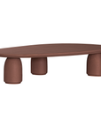 Lantara coffee table in cinnabar clay finish with elongated oval top and three rounded sculptural legs.
