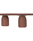 Lantara coffee table in cinnabar clay finish with elongated oval top and three rounded sculptural legs.