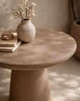 Lantara side table in nomad dune finish styled with a ceramic vase in a warm neutral interior setting.