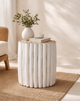 Latte white side table with sculptural fluted form styled on a woven rug in a calm modern organic interior