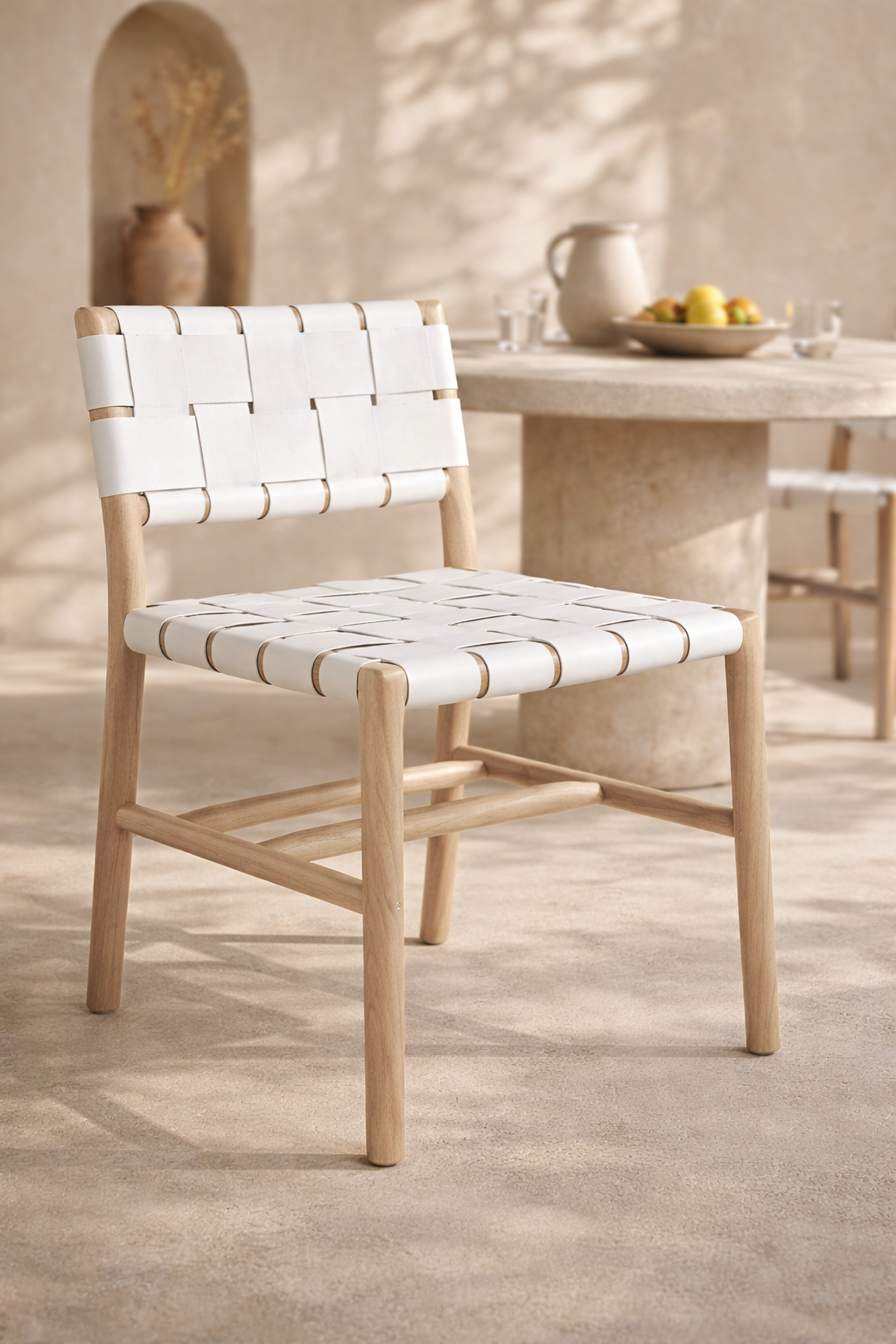 Lazzy dining chair with natural timber frame and white woven leather seat in a warm mediterranean inspired setting