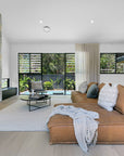 A luxurious tan leather modular sofa set in a contemporary living room with a striking stone fireplace, complemented by a modern accent chair with a black metal frame