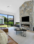 A luxurious tan leather modular sofa set in a contemporary living room with a striking stone fireplace, complemented by a modern accent chair with a black metal frame