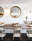 Modern restaurant interior featuring wooden dining chairs with woven rope seats and natural wood tabletops, creating a relaxed coastal ambiance