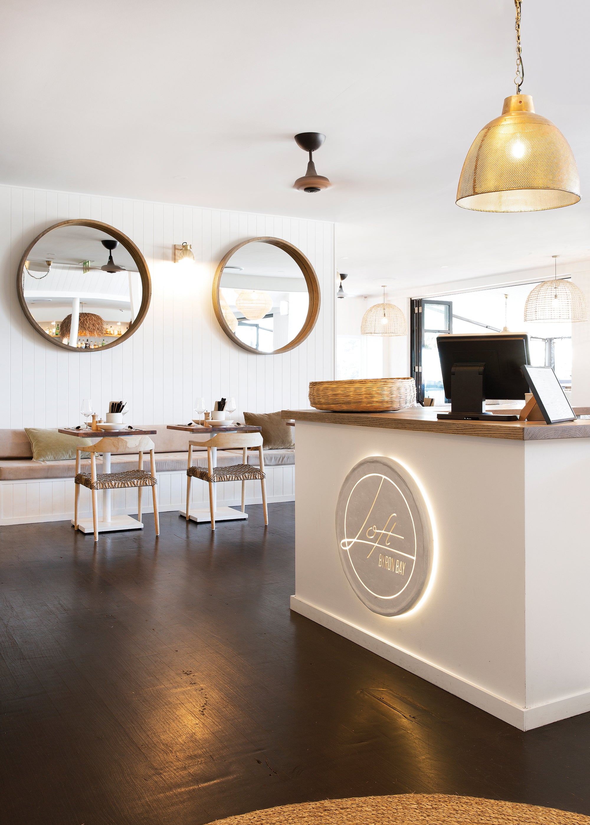 Modern restaurant interior featuring wooden dining chairs with woven rope seats and natural wood tabletops, creating a relaxed coastal ambiance.