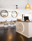 Modern restaurant interior featuring wooden dining chairs with woven rope seats and natural wood tabletops, creating a relaxed coastal ambiance.