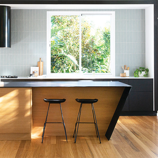 modern organic australian kitchen with two black barstools at a timber island and soft neutral styling