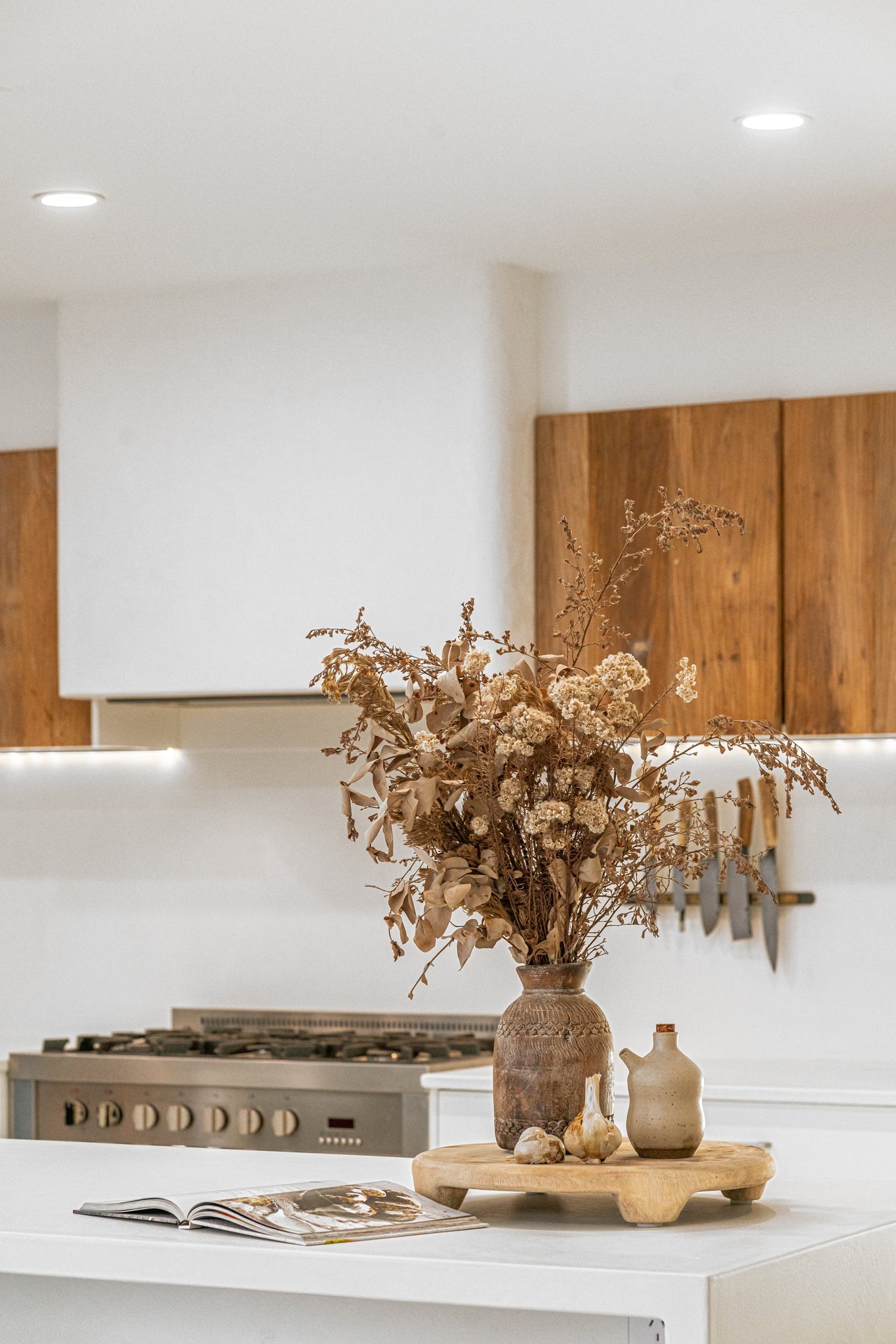 Lumara cheese plate in solid natural wood with round profile, visible timber grain and low pedestal feet.