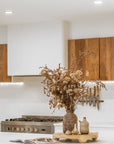 Lumara cheese plate in solid natural wood with round profile, visible timber grain and low pedestal feet.
