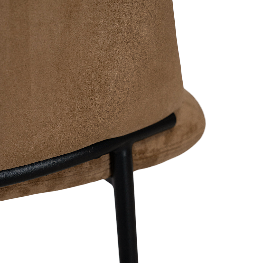 Lumo dining chair in hazelnut with soft upholstered seat and curved backrest on slim black legs shown in a clean minimal setting.