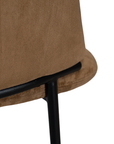 Lumo dining chair in hazelnut with soft upholstered seat and curved backrest on slim black legs shown in a clean minimal setting.