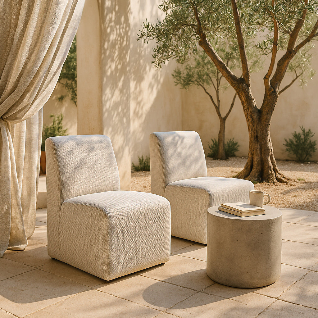 Pair of Martinique Low Chairs styled outdoors with a round concrete side table, neutral palette and Mediterranean-inspired garden setting