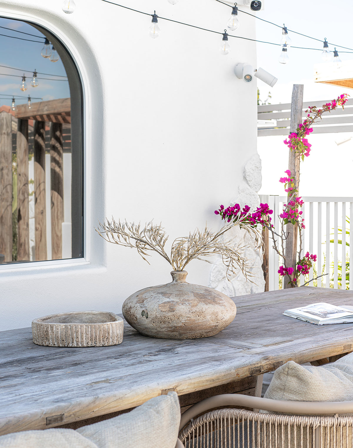 Mayi handcrafted terracotta bowl and Katanga Vase styled on a rustic timber outdoor dining table in a relaxed coastal setting.