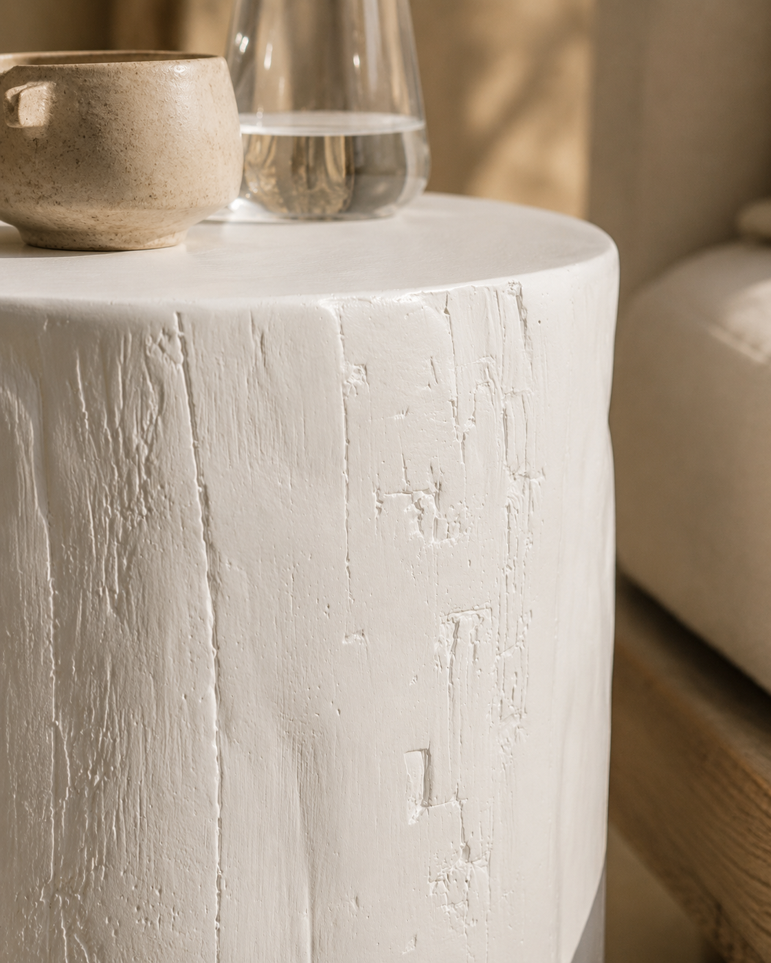 White magnesium oxide Meera stool styled beside an outdoor lounge creating a light and tranquil setting with soft textures and natural Mediterranean inspired warmth.