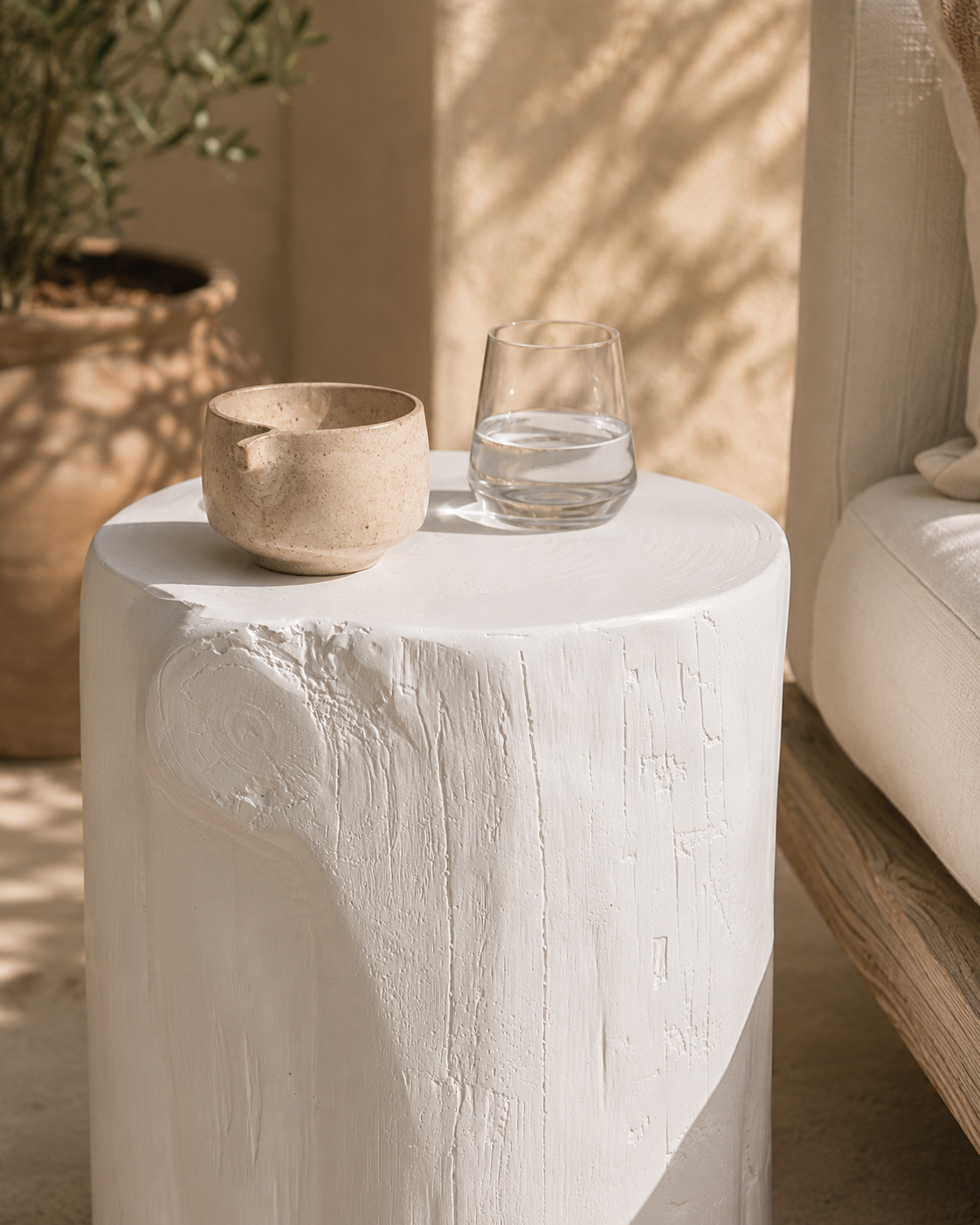 White magnesium oxide Meera stool styled beside an outdoor lounge creating a light and tranquil setting with soft textures and natural Mediterranean inspired warmth.