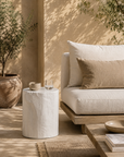 White magnesium oxide Meera stool styled beside an outdoor lounge creating a light and tranquil setting with soft textures and natural Mediterranean inspired warmth.