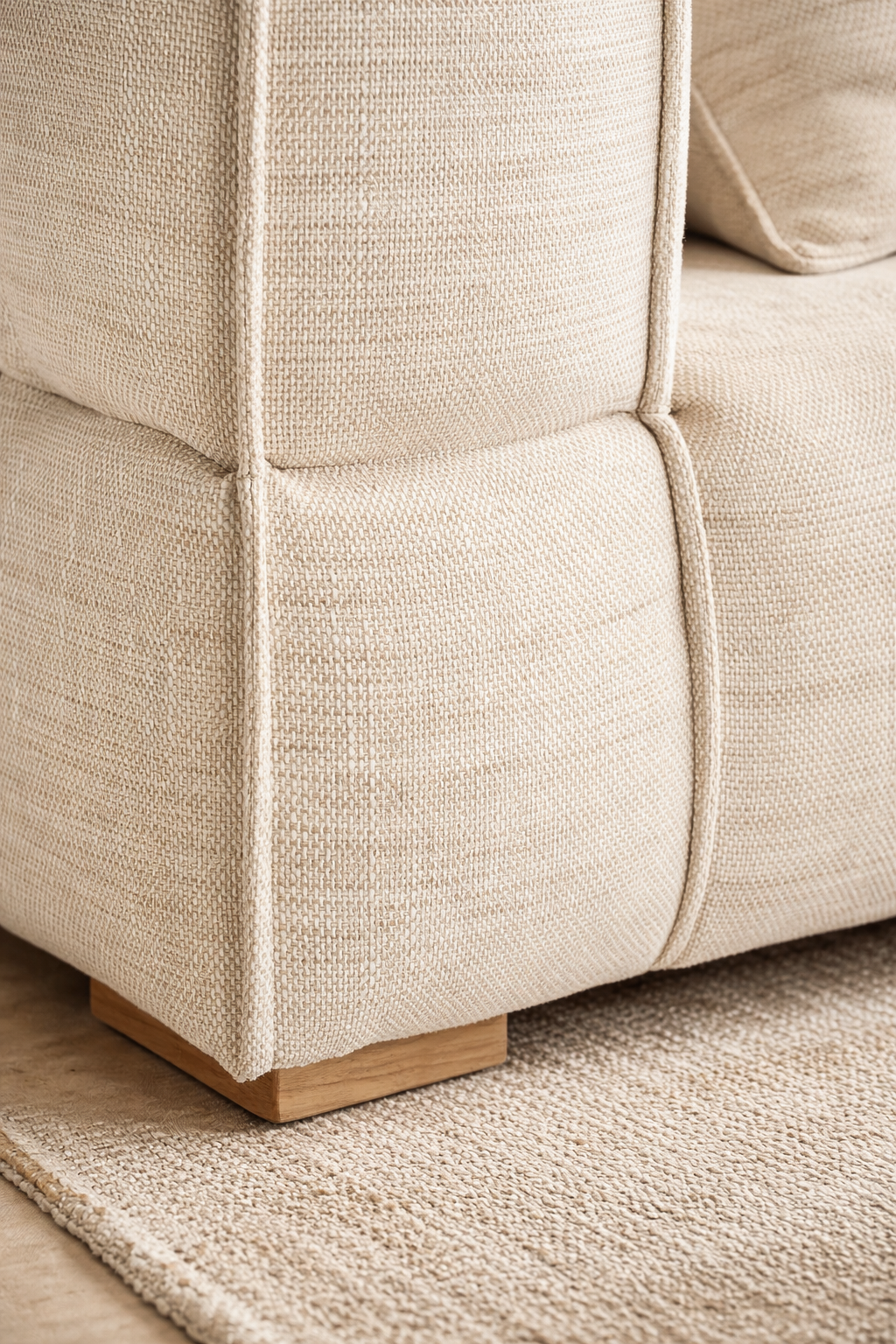 Melonee modular sofa in soft beige upholstery styled in a warm neutral living room with plaster walls, woven rug and round timber coffee table.