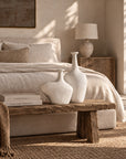 KULALA Living Meraki whitewashed fibre cement vases styled on a rustic timber bench in a warm neutral bedroom.