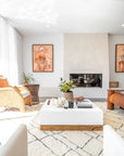 A beautifully styled modern coastal living room featuring a white and wood coffee table, textured neutral decor, and a built-in fireplace. The space is accented with woven and rattan furniture, tribal artwork, and soft natural light, creating a warm and inviting atmosphere