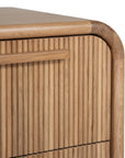 A modern oak bedside table from KULALA Living, featuring a curved silhouette and storage drawers. Crafted from natural wood, this minimalist piece enhances any bedroom with its warm, organic aesthetic