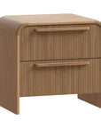 A modern oak bedside table from KULALA Living, featuring a curved silhouette and storage drawers. Crafted from natural wood, this minimalist piece enhances any bedroom with its warm, organic aesthetic