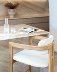 Rubberwood counter-height chair with curved frame and ivory boucle upholstery, styled at a travertine kitchen island with soft neutral tones and minimal decor.