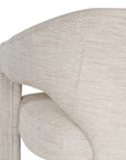 Contemporary upholstered armchair in a soft beige fabric, featuring a sculptural curved frame and plush seating for a modern, sophisticated look.