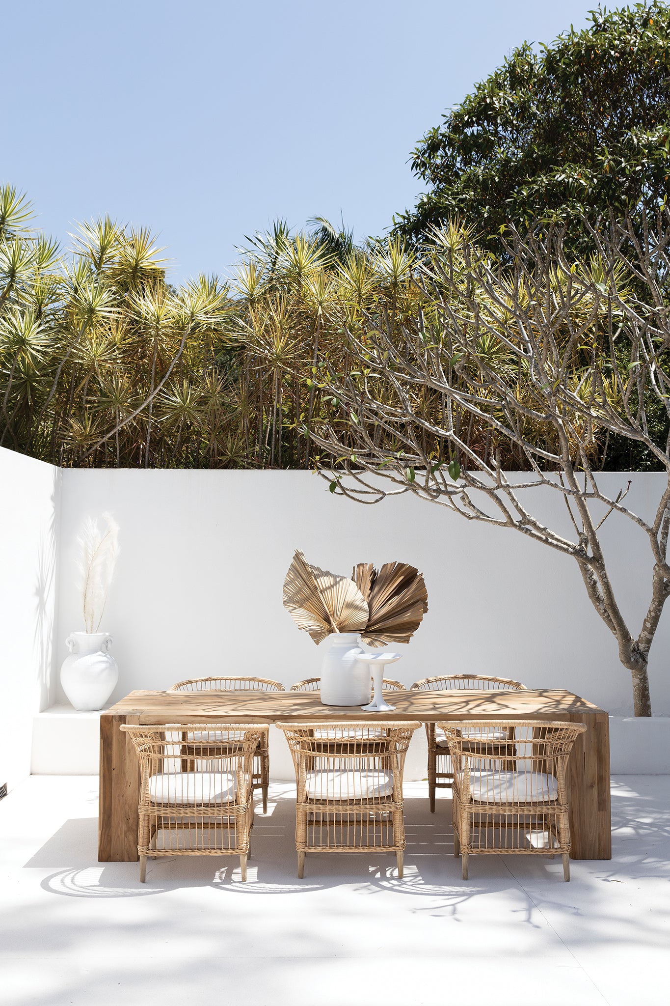 Nakula blonde rattan dining chairs styled around a timber table in a sunlit mediterranean inspired australian courtyard setting